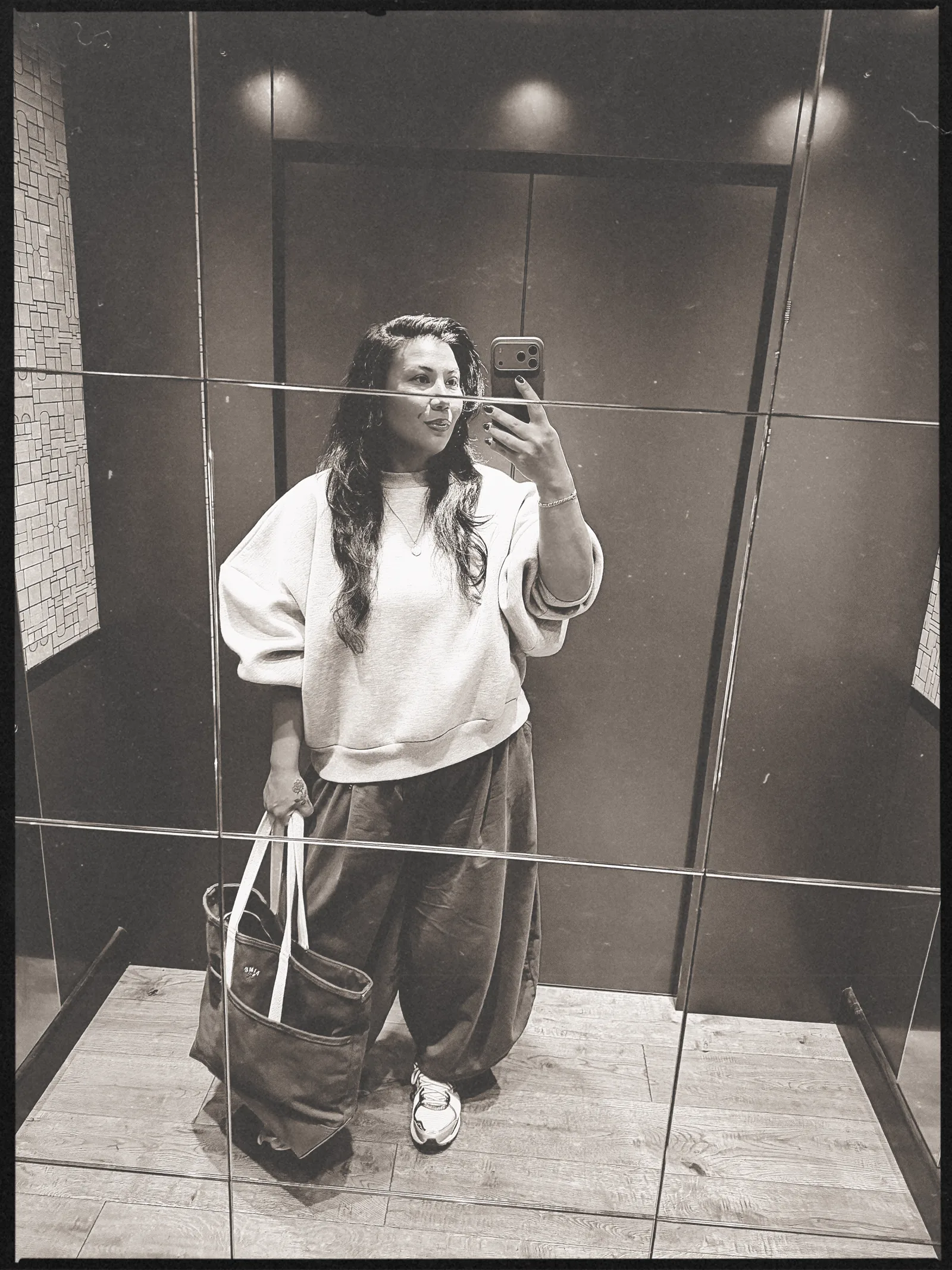 Ana Pryor taking a full-length mirror selfie in a tiled hallway
